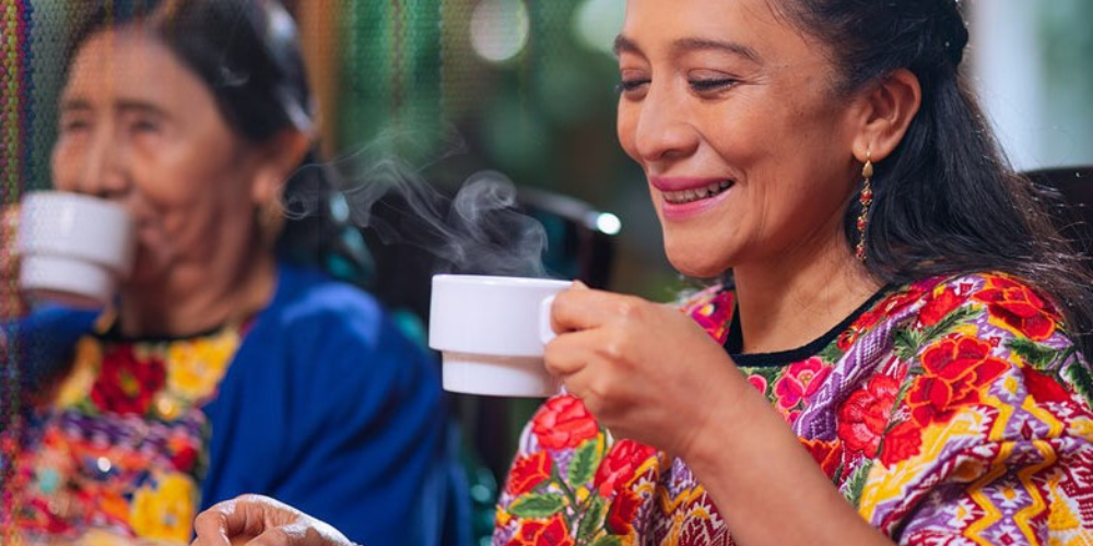 Two Peruvian women drink from tea cups