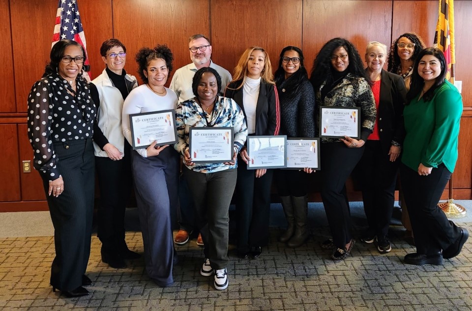 a group of professionals pose for photo while holding certificates