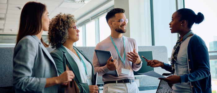 group of four faculty chatting in an office setting