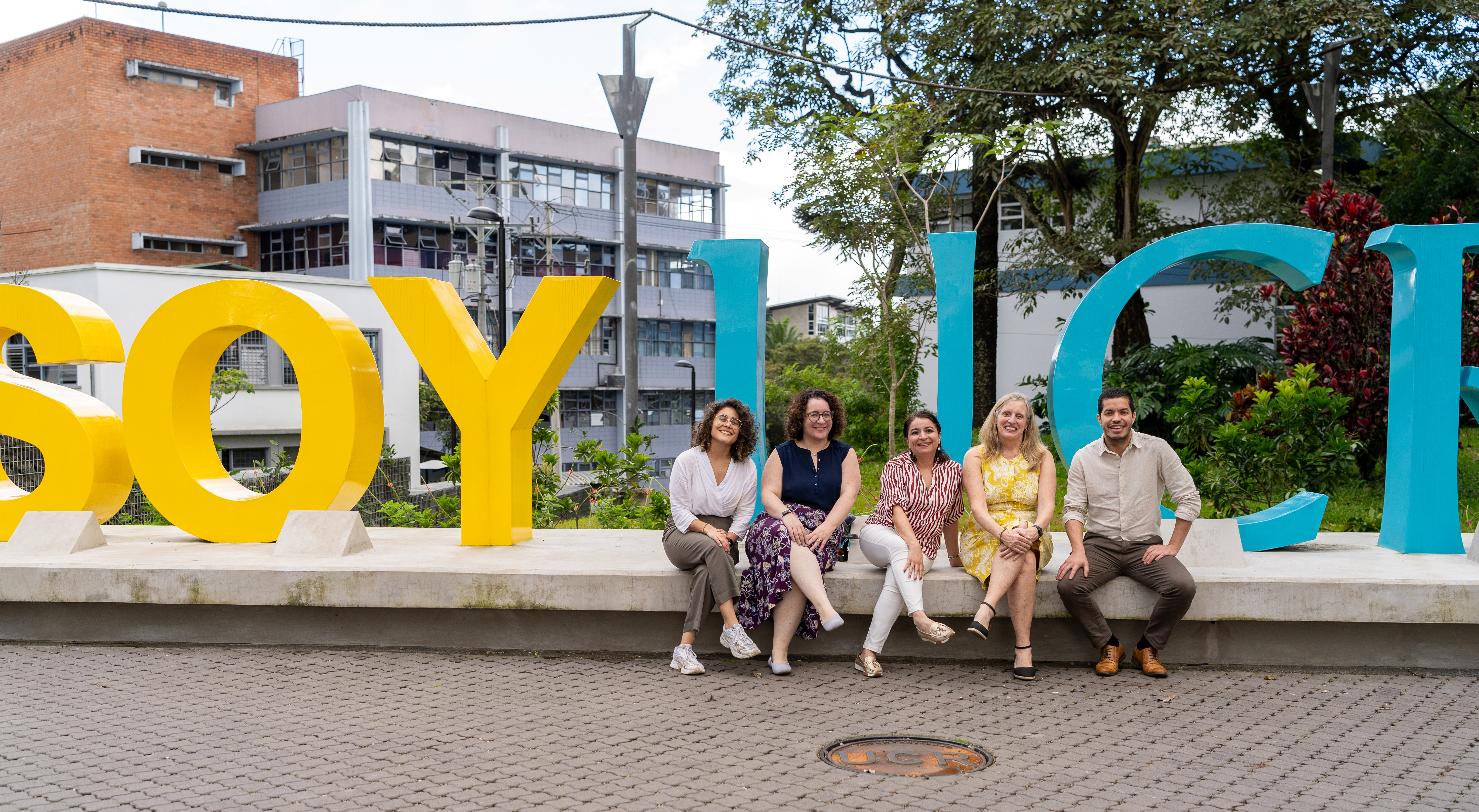 UMB faculty sit in front of a large sign that says SOY UCR