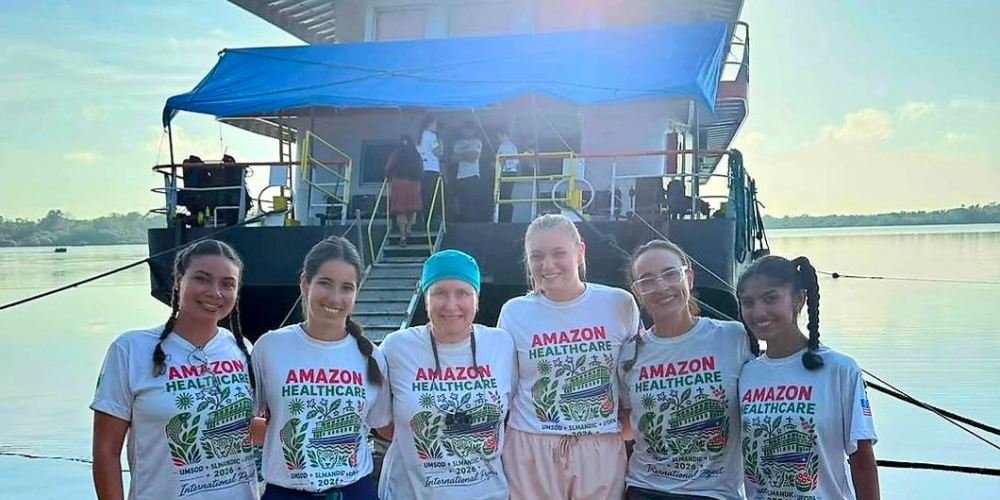 Dentistry students pose for a photo on the shores of the Amazon beside a medical boat.