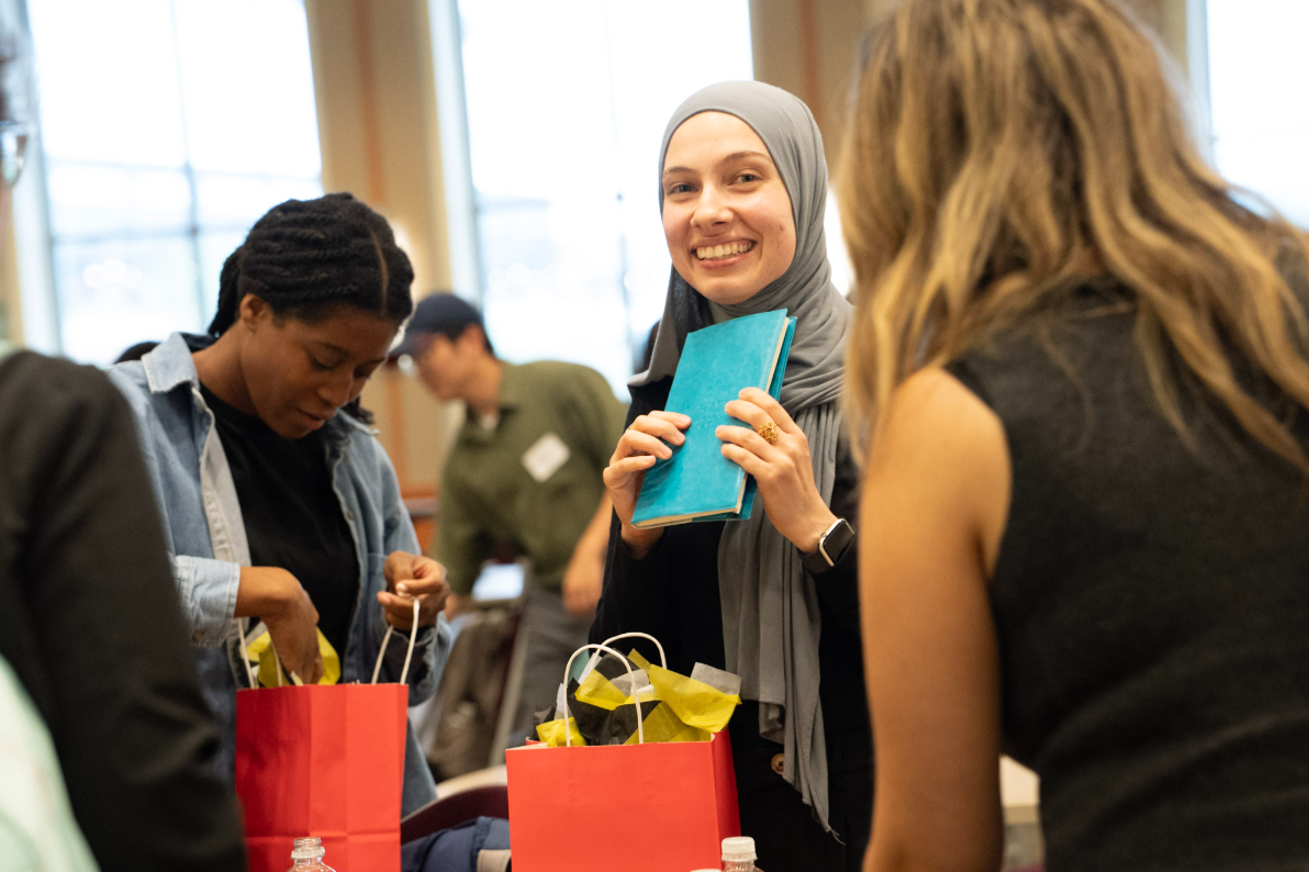 A student holds a journal while others look through goodie bags.