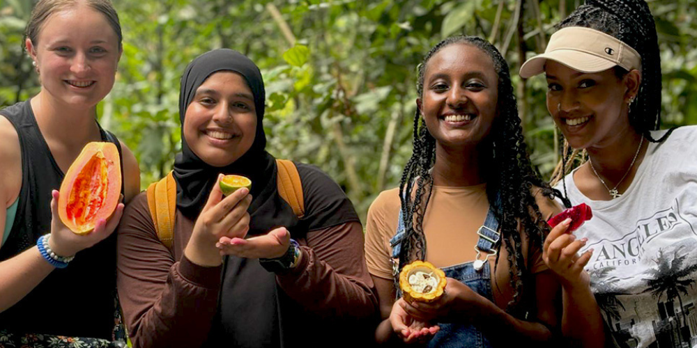 Nursing students hold tropical fruit outside in a forest
