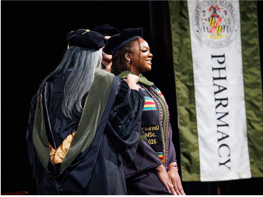 A graduate gets hooded at the University of Maryland School of Pharmacy PharmD Convocation in May 2026.