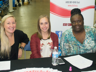 Center for Urban Families client service coordinator Kari Price, left, and School of Social Work students Alyssa McCreary, center, and Fatima Askew, right, offer resources to participants at Project Homeless Connect.
 
