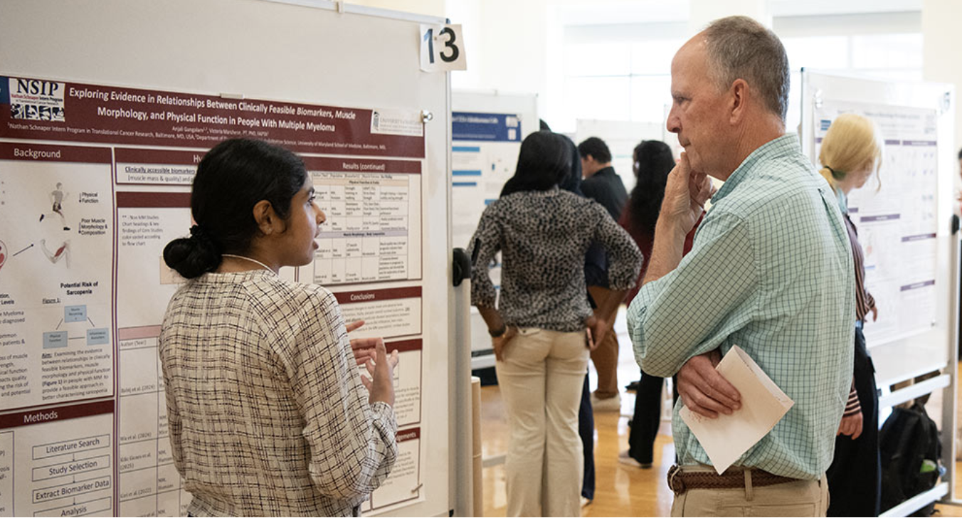 Student scholar presents poster to faculty member