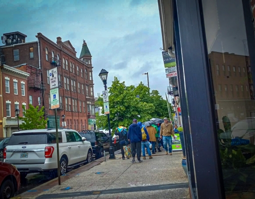 a group of people stand in line on the sidewalk in an urban area