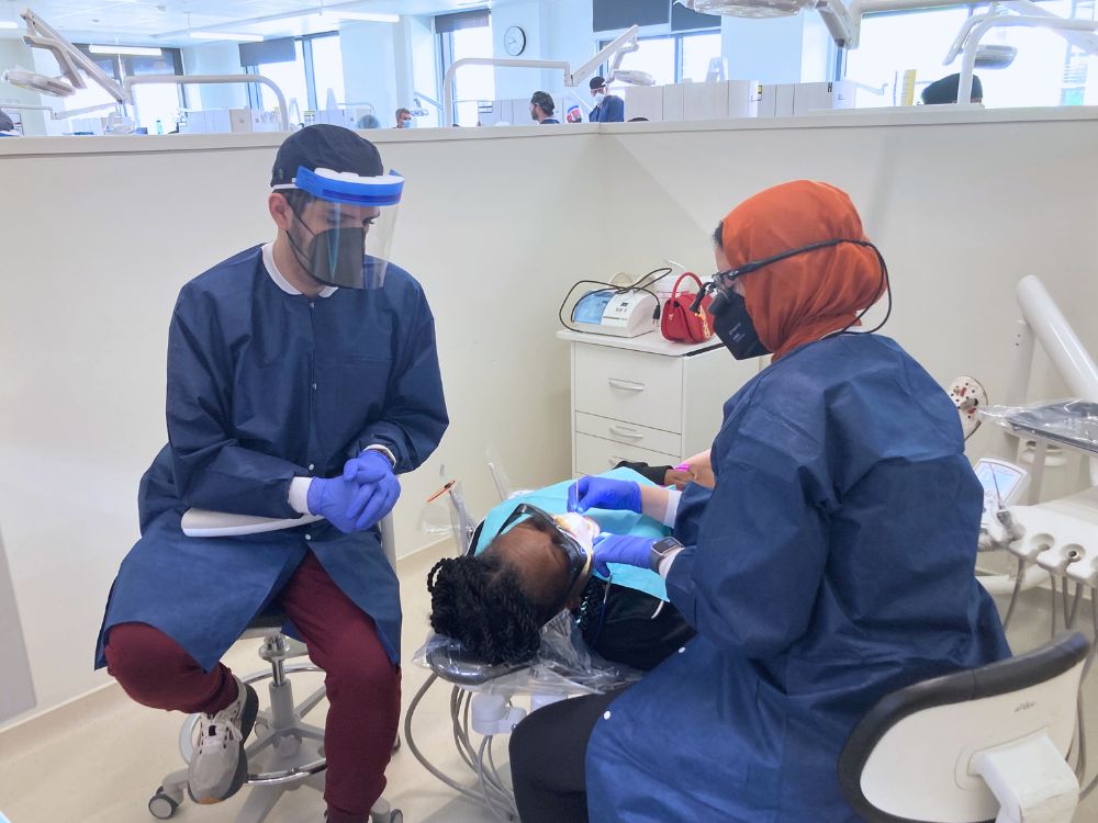 Elyas Azamy (left) and Sarah Abdelwahab (right) treat a patient at the spring Mission of Mercy Clinic at Shady Grove