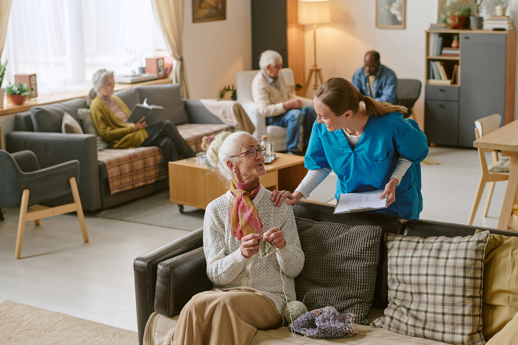 A nurse checking in with a woman in an assisted living common area